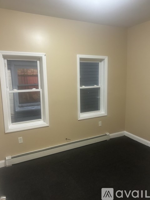 A room with two windows and a black floor.