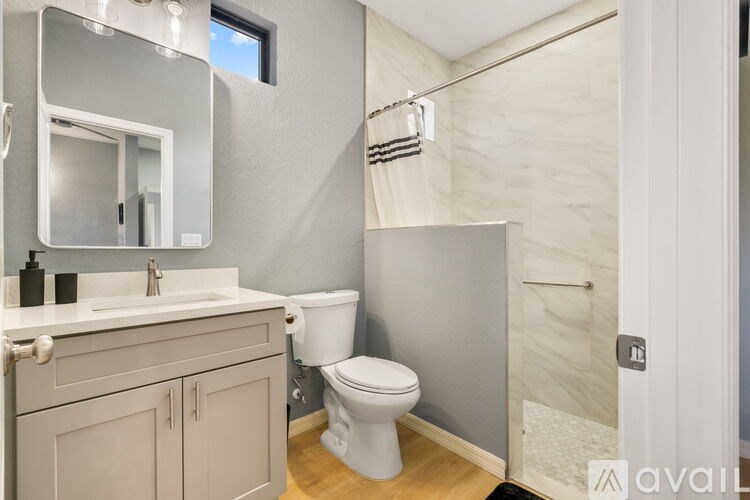 A bathroom with a toilet, sink, and a mirror.