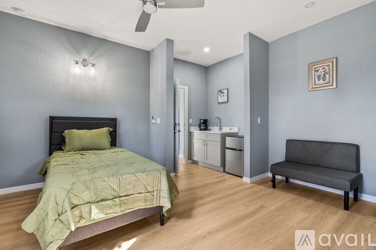A bedroom with a bed, a bench, and a fan.