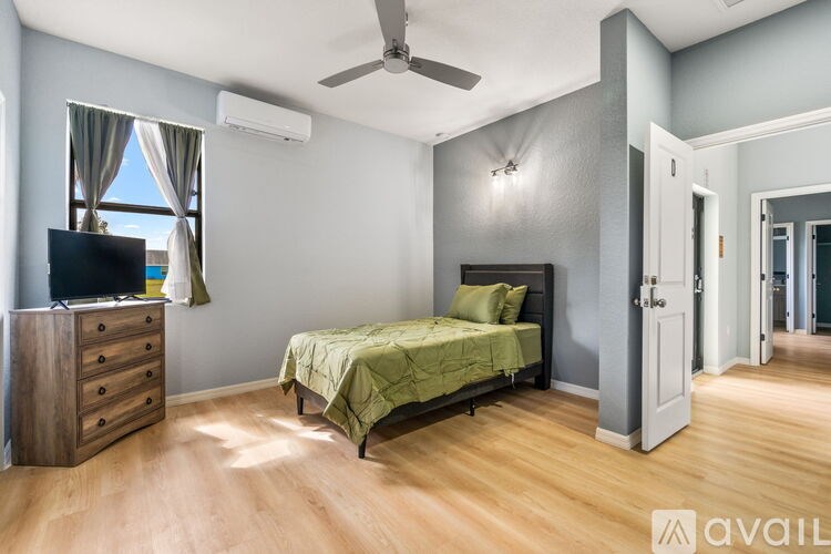 A bedroom with a bed, dresser, and a ceiling fan.