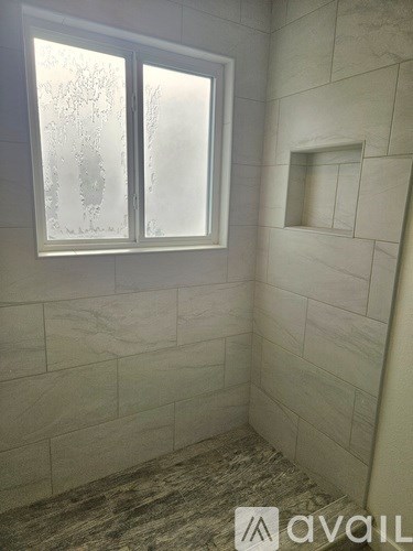 A bathroom with a window and tiled walls.