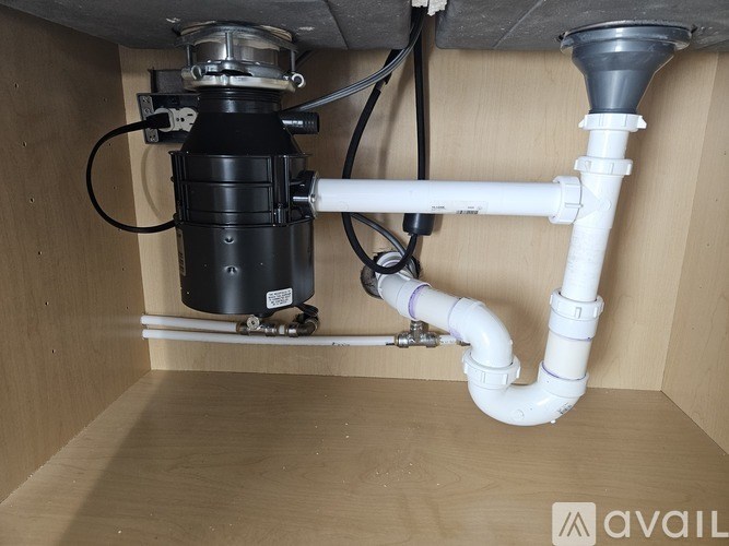 A black and white plumbing fixture is installed in a wooden cabinet.