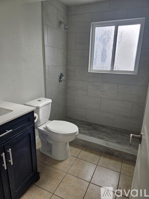 A bathroom with a toilet, sink, and a window.