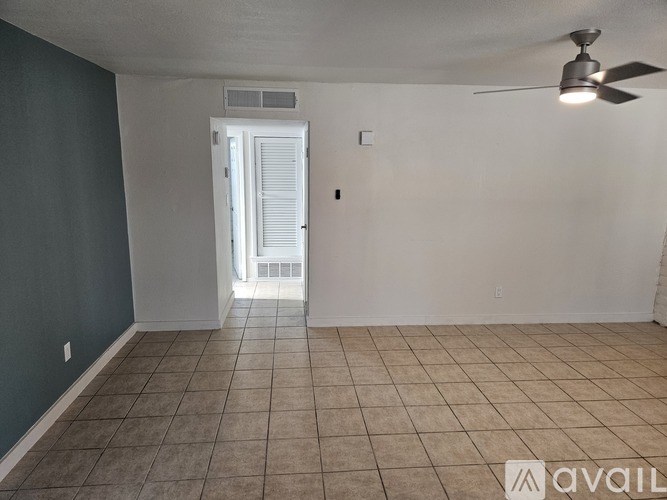 A room with a ceiling fan and a door leading to a balcony.