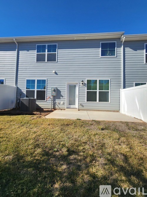 A grey house with a white fence and a small yard.