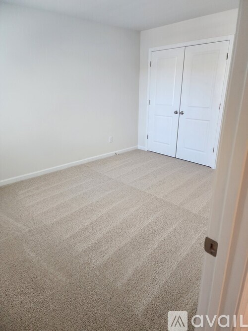 A room with a carpeted floor and a white door.