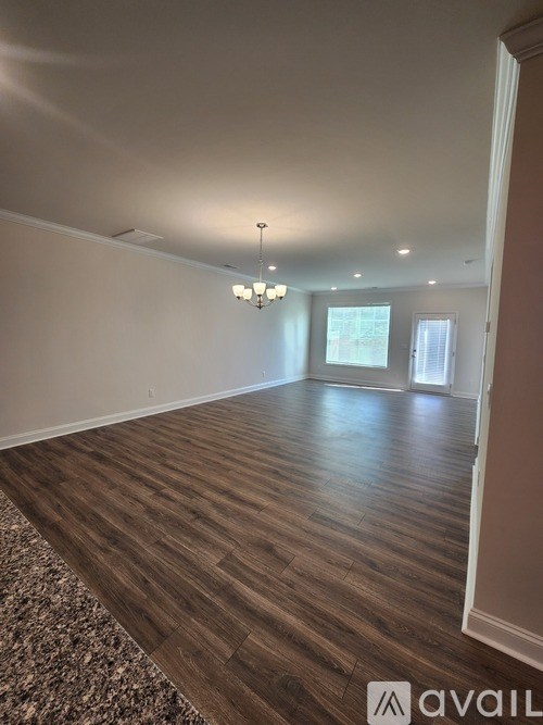 A room with wooden flooring and a chandelier.