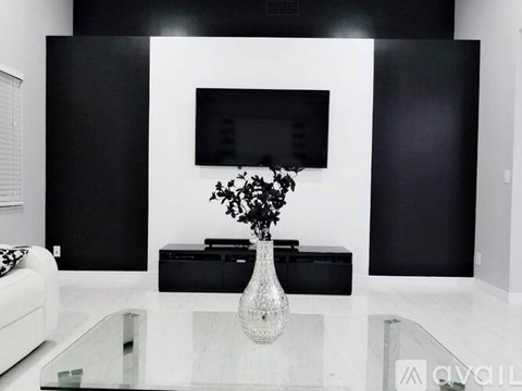 A black and white living room with a glass table and a vase of flowers.