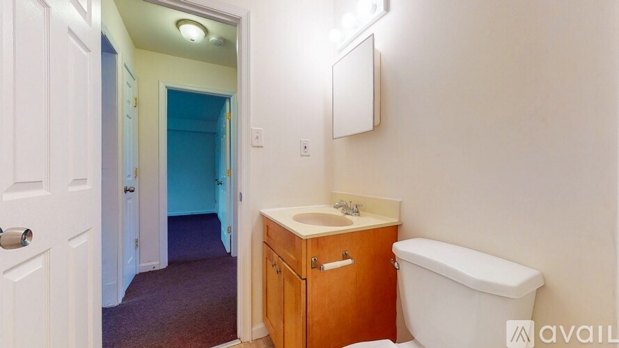 A bathroom with a toilet, sink, and a cabinet.