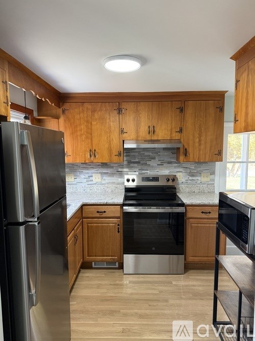 A kitchen with wooden cabinets and a stainless steel refrigerator.