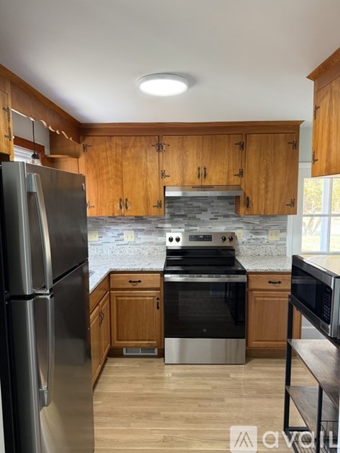 A kitchen with wooden cabinets and a stainless steel refrigerator.