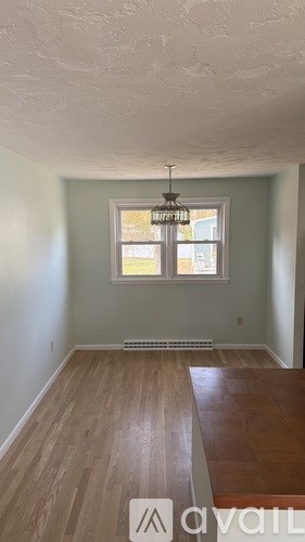 A room with wooden floors and a window with a view of a building outside.