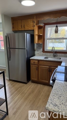 A kitchen with a refrigerator, sink, and wooden cabinets.