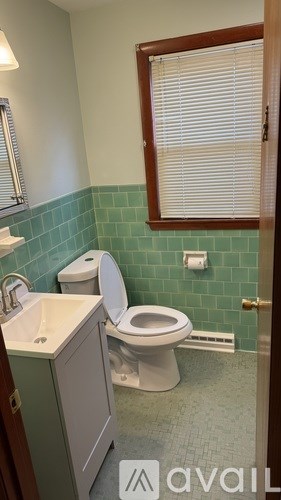 A bathroom with a toilet, sink, and a window.