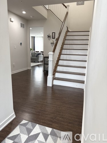 A staircase with a white railing and wooden steps leads to a living room.