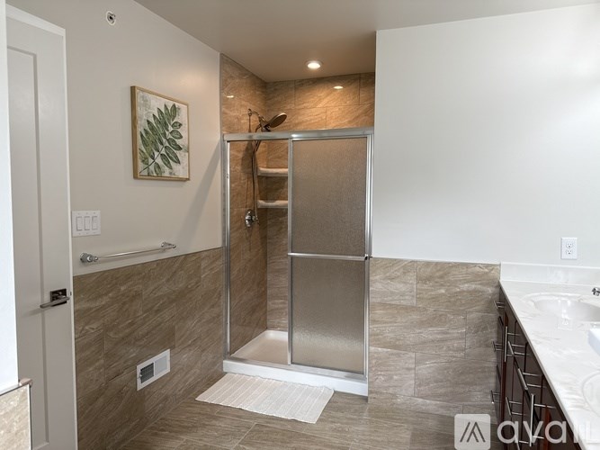 A modern bathroom with a walk-in shower and a white sink.