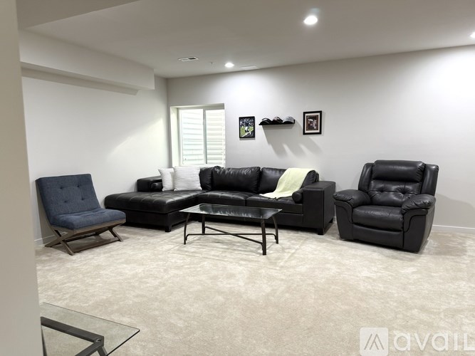 A living room with a black leather couch, chair, and ottoman.