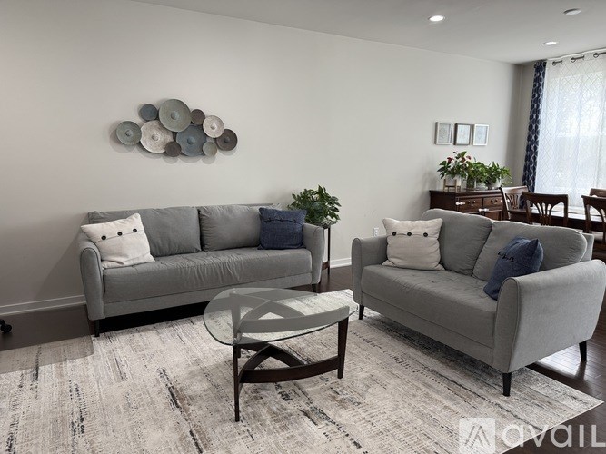 A living room with a grey couch, a coffee table, and a wall art.