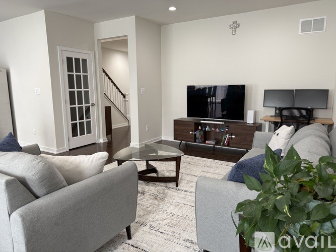 A living room with a grey couch, a coffee table, a television, and a staircase.