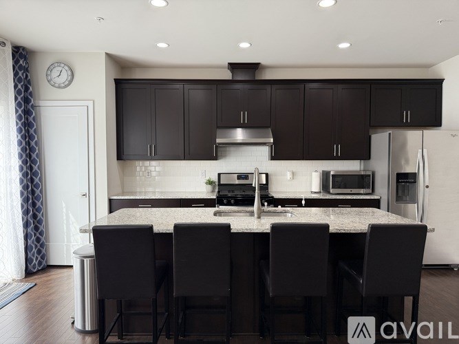 A modern kitchen with a large island and dark cabinets.