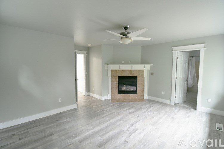 A living room with a fireplace and a ceiling fan.