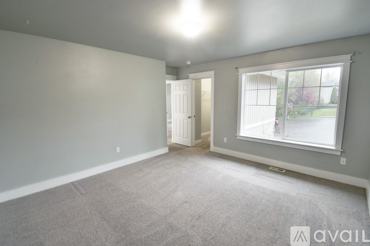 A room with a carpeted floor, a window, and a door.