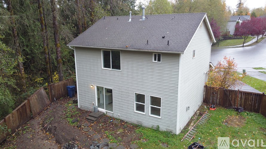 A house with a grey roof and a grey siding is surrounded by a wooden fence.