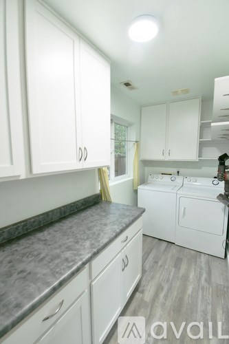 A kitchen with white cabinets and a washing machine.