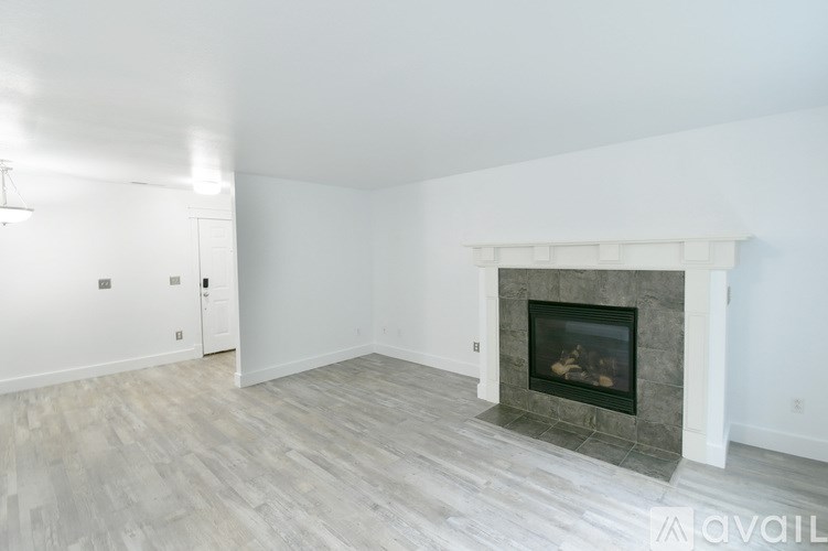 A large empty room with a fireplace and wood flooring.