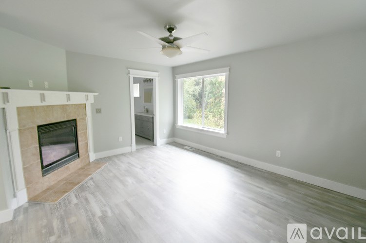 A spacious living room with a fireplace and a ceiling fan.