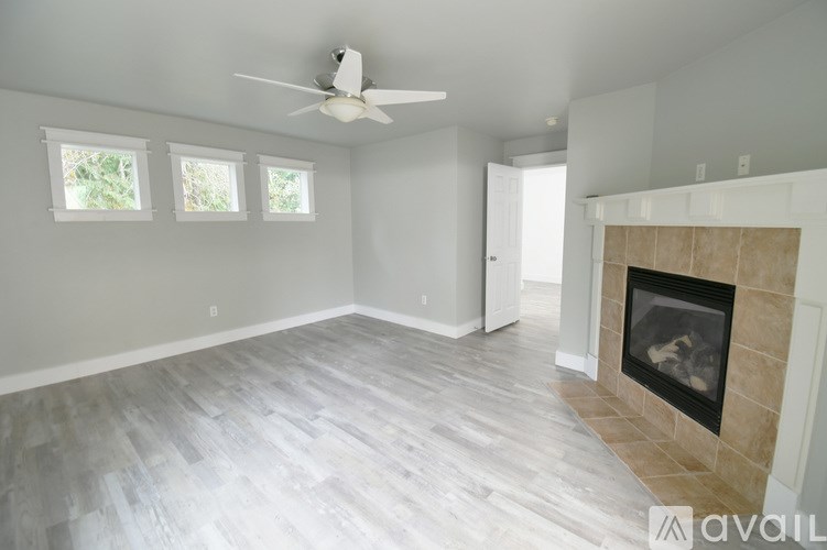 A living room with a fireplace and a ceiling fan.