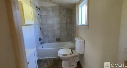 A bathroom with a toilet, tub, and towel rack.