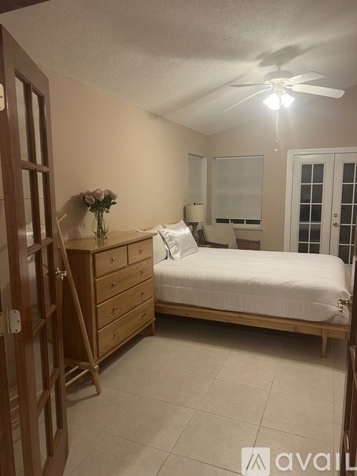 A bedroom with a bed, dresser, and ceiling fan.