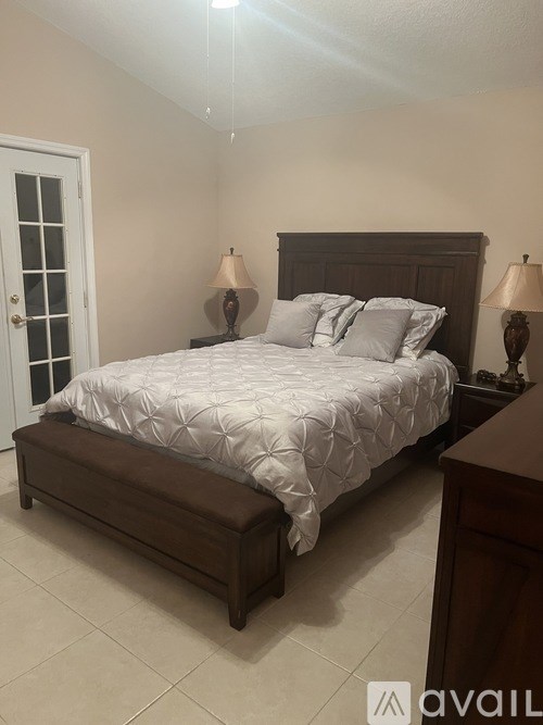 A bedroom with a large bed and two lamps.