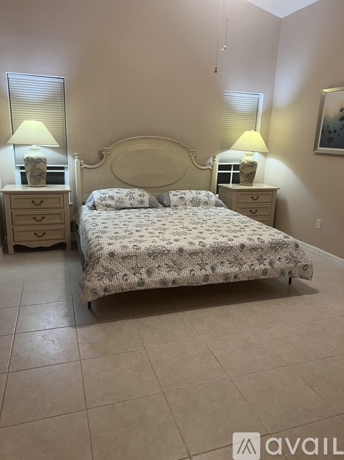 A bedroom with a bed, two nightstands, and lamps.