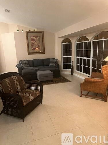 A living room with a sofa, two chairs, and a painting on the wall.