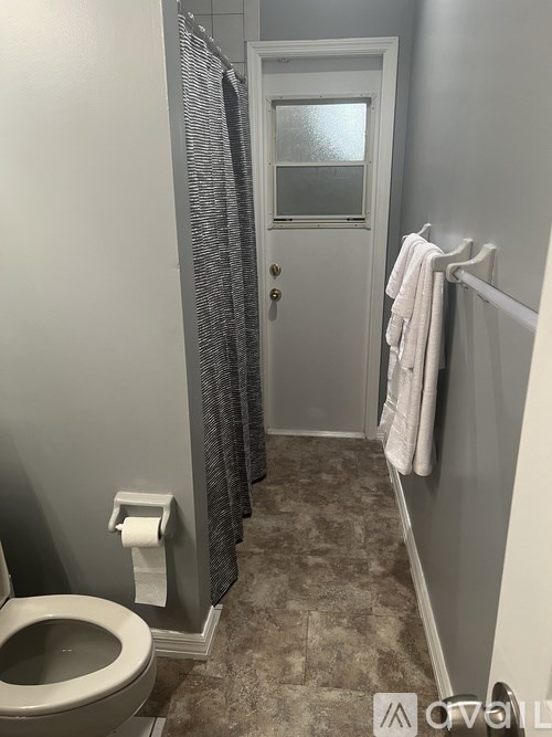A bathroom with a toilet, a shower curtain, and a towel rack.