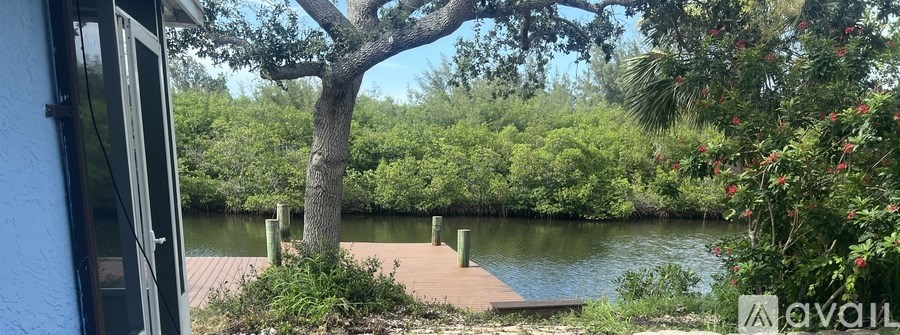 A view from a window looking out to a dock and a body of water surrounded by greenery.