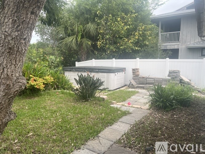 A white fence and a small garden with a white house in the background.