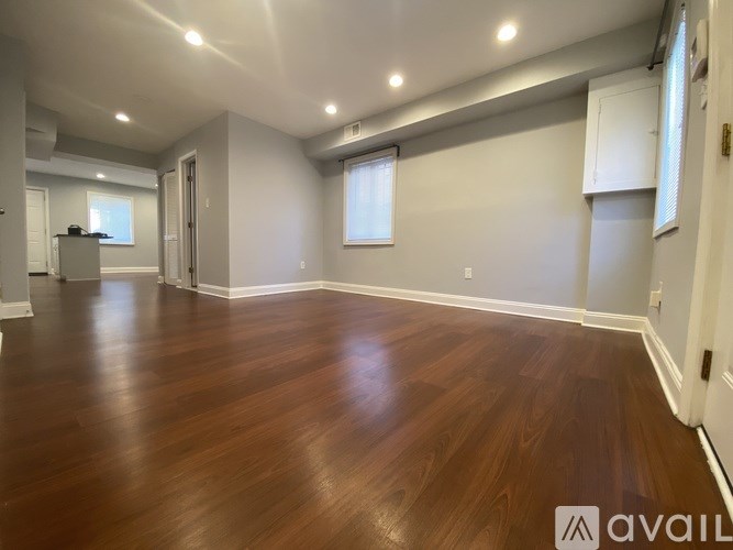 A spacious room with wooden flooring and white walls.