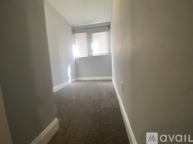 A room with a carpeted floor and a window with blinds.