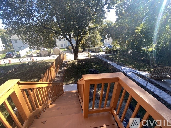 A wooden deck with a railing overlooking a tree and a yard.