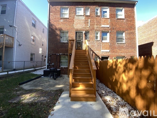 A wooden staircase leads up to a brick building with a small patio area in front.