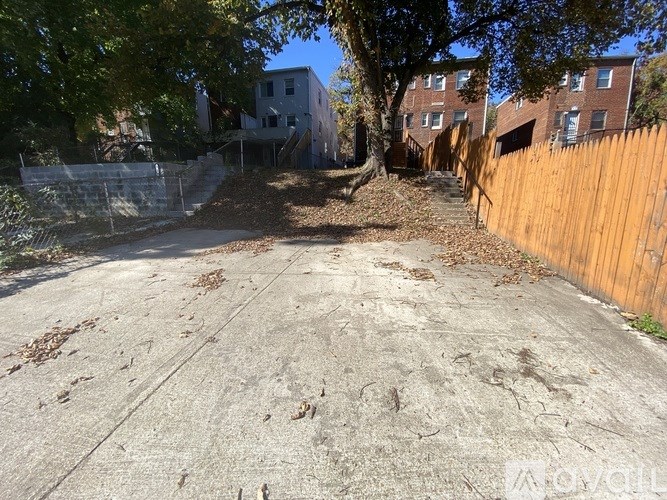 A concrete area with a fence and trees in the background.