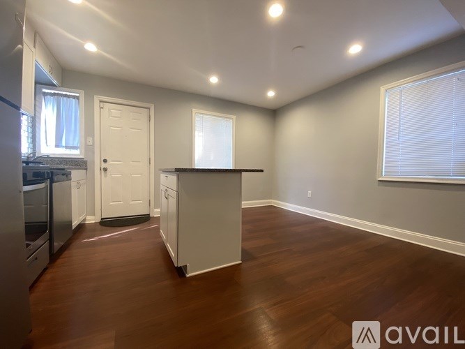 A kitchen with a white door and a wooden floor.