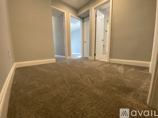 A carpeted room with a doorway leading to another room.