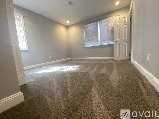 A room with a carpeted floor and a door on the right side.