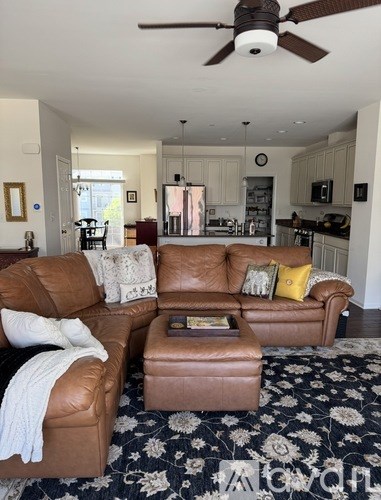A living room with a brown leather couch and ottoman.