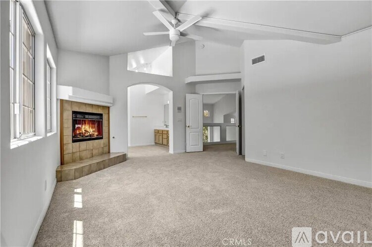 A spacious living room with a fireplace and a carpeted floor.