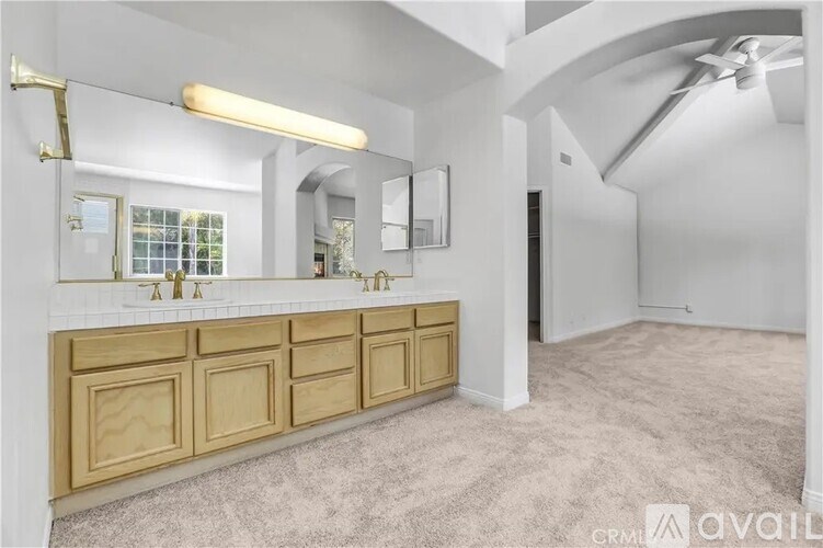 A bathroom with a vanity, mirror, and light fixture.